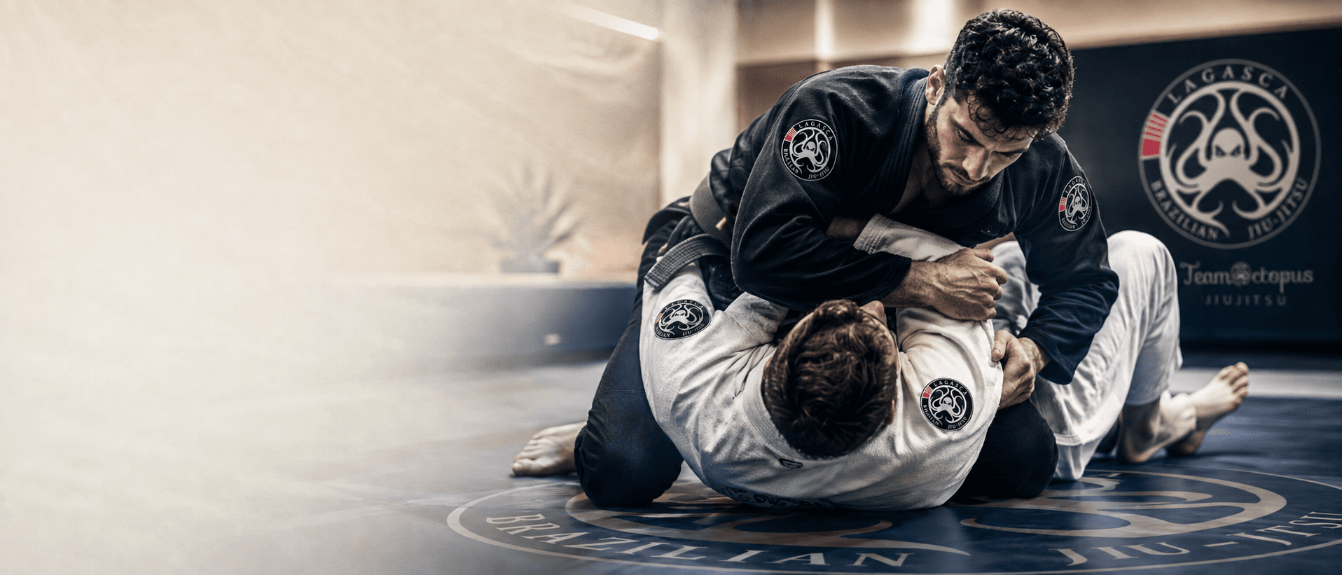 Two Team Octopus athletes training Brazilian Jiu-Jitsu on the mats